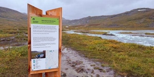 Informasjonstavle ved sti gjennom norsk fjellterreng og våtmark